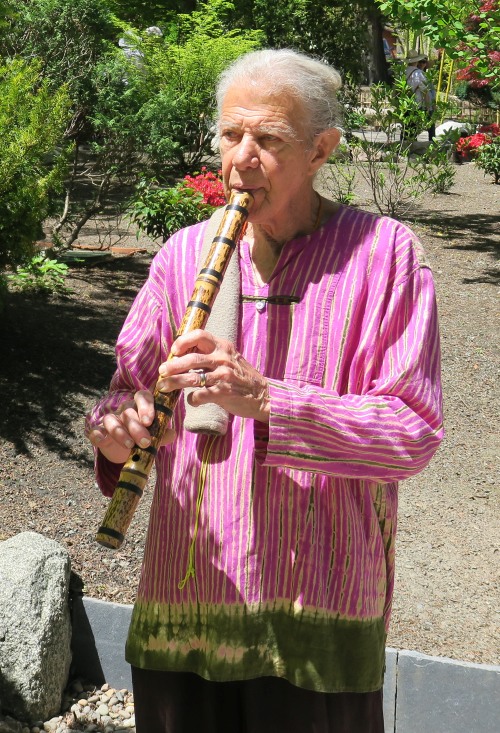 Viktor Novick stands in the garden playing a flute